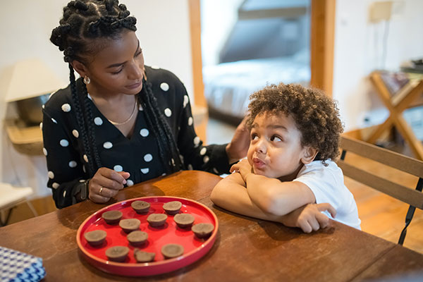 A boy sitting at a table with his mother