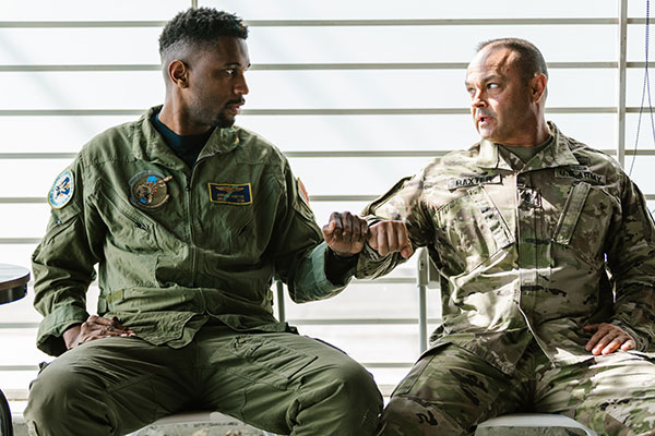 two middle age men in military uniforms bump fists